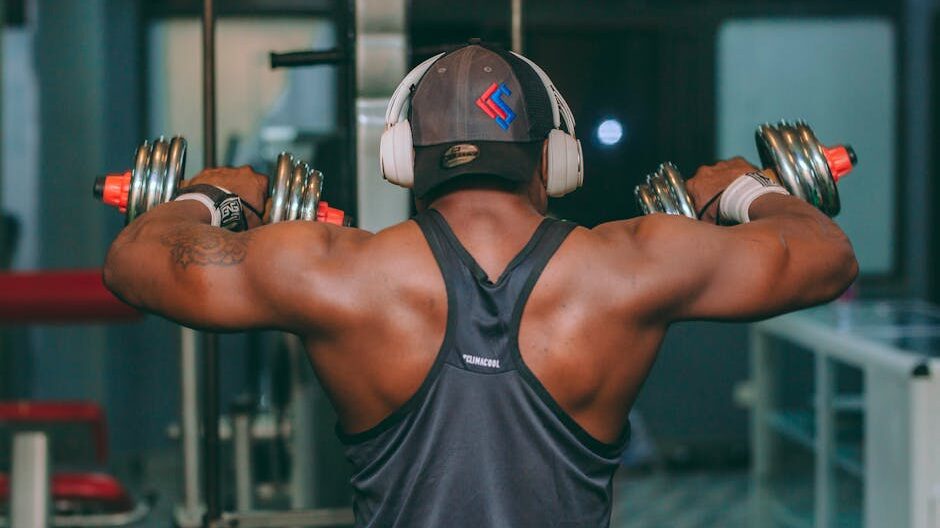 Focused male lifting dumbbells in gym, demonstrating strength and concentration.